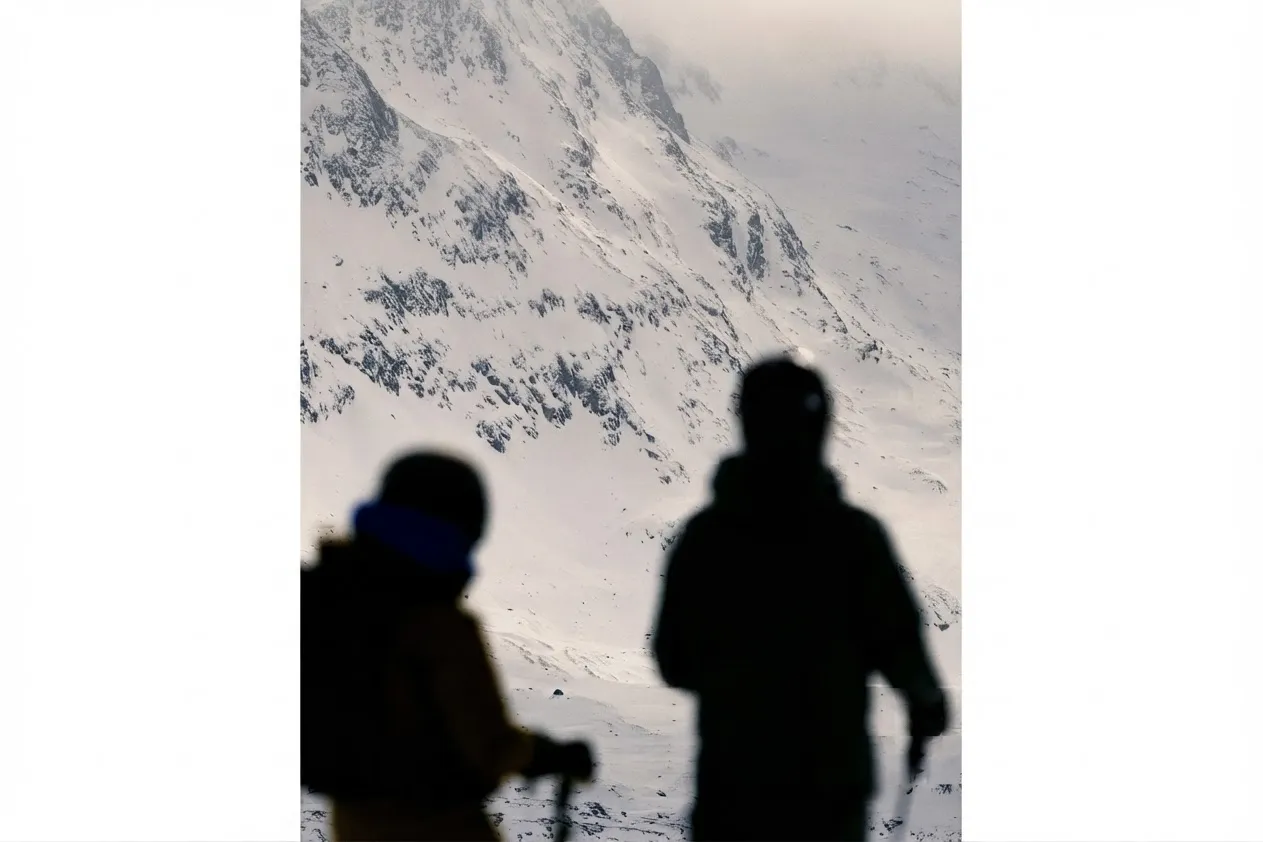 Two skiers looking out over a snow-covered mountain face
